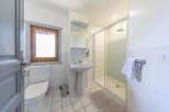 This bright and airy bathroom features a modern shower, a pedestal sink, and a toilet.
