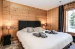 This cozy bedroom features a stunning wooden wall, creating a warm and inviting atmosphere.