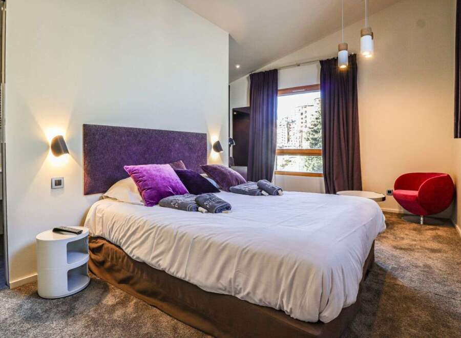 Experience luxury in this stunning bedroom featuring a plush king-size bed with vibrant purple accents.