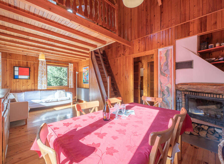 Step into this charming wooden cabin, featuring a cozy living space with a fireplace and a dining area perfect for gatherings.