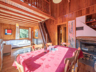 Step into this charming wooden cabin, featuring a cozy living space with a fireplace and a dining area perfect for gatherings.