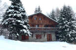 Nestled amidst a snowy landscape, this charming wooden chalet offers a cozy retreat.