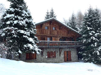 Nestled amidst a snowy landscape, this charming wooden chalet offers a cozy retreat.