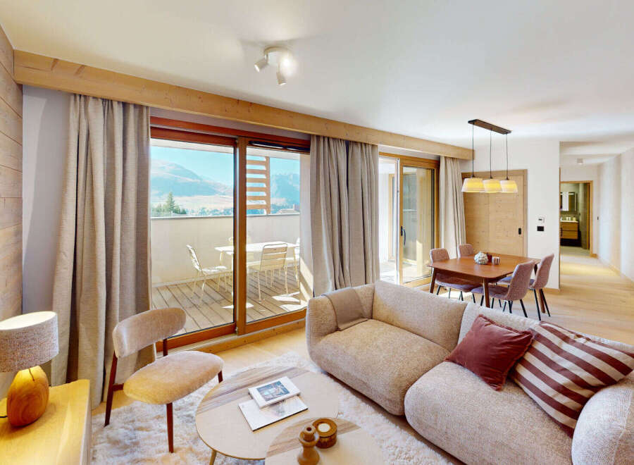 Experience modern mountain living in this beautifully appointed apartment, featuring a spacious living area with a cozy sofa and a dining set perfect for family meals.