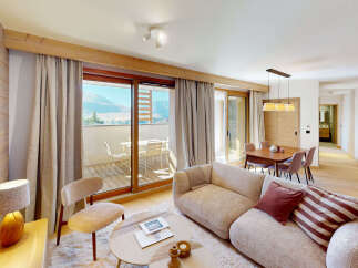 Experience modern mountain living in this beautifully appointed apartment, featuring a spacious living area with a cozy sofa and a dining set perfect for family meals.