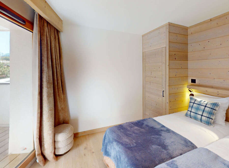 Experience cozy mountain living in this charming bedroom featuring two twin beds adorned with plush blue and plaid bedding.