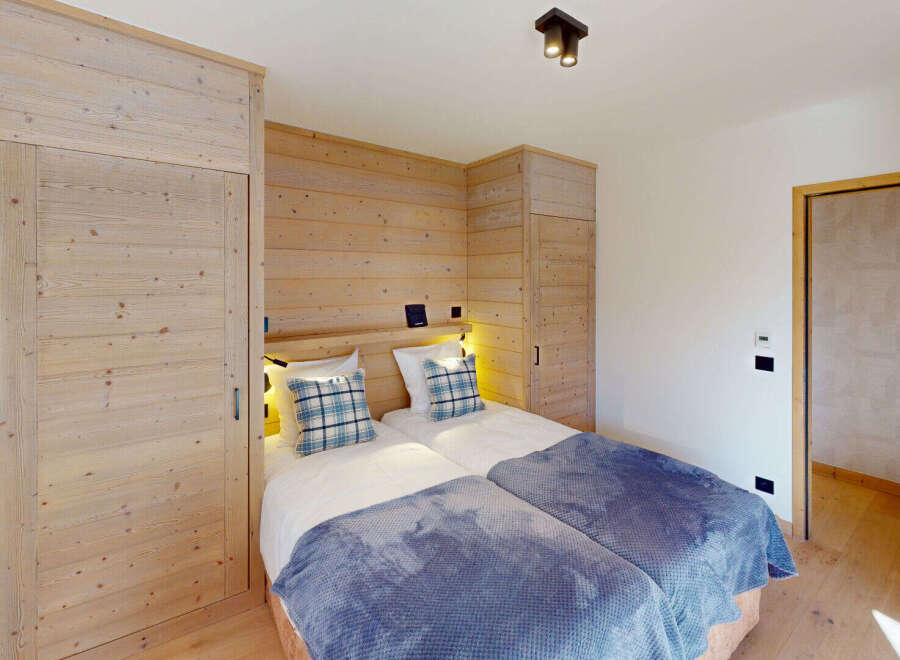 This charming bedroom features two twin beds adorned with cozy blue plaid pillows and plush blankets, perfect for a restful night's sleep.