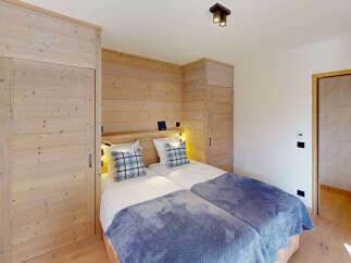 This charming bedroom features two twin beds adorned with cozy blue plaid pillows and plush blankets, perfect for a restful night's sleep.