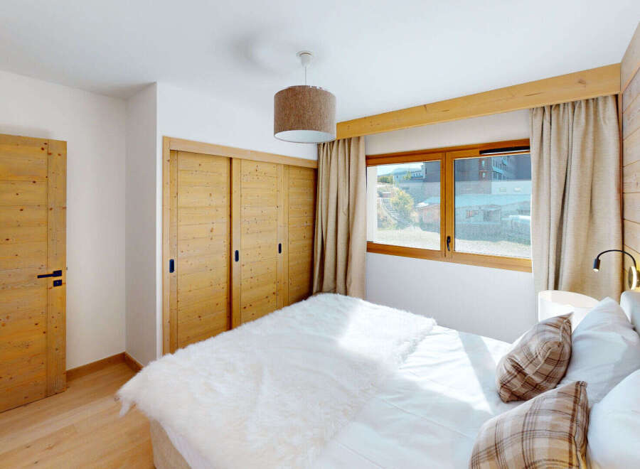 Experience cozy mountain living in this charming bedroom featuring warm wooden accents and a plush white duvet.