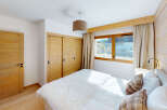 Experience cozy mountain living in this charming bedroom featuring warm wooden accents and a plush white duvet.