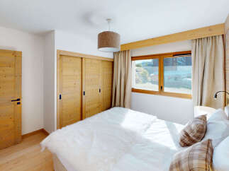 Experience cozy mountain living in this charming bedroom featuring warm wooden accents and a plush white duvet.