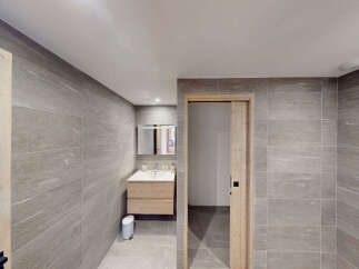 Experience modern comfort in this beautifully appointed bathroom, featuring sleek grey tiled walls and a floating wooden vanity with a clean white sink.
