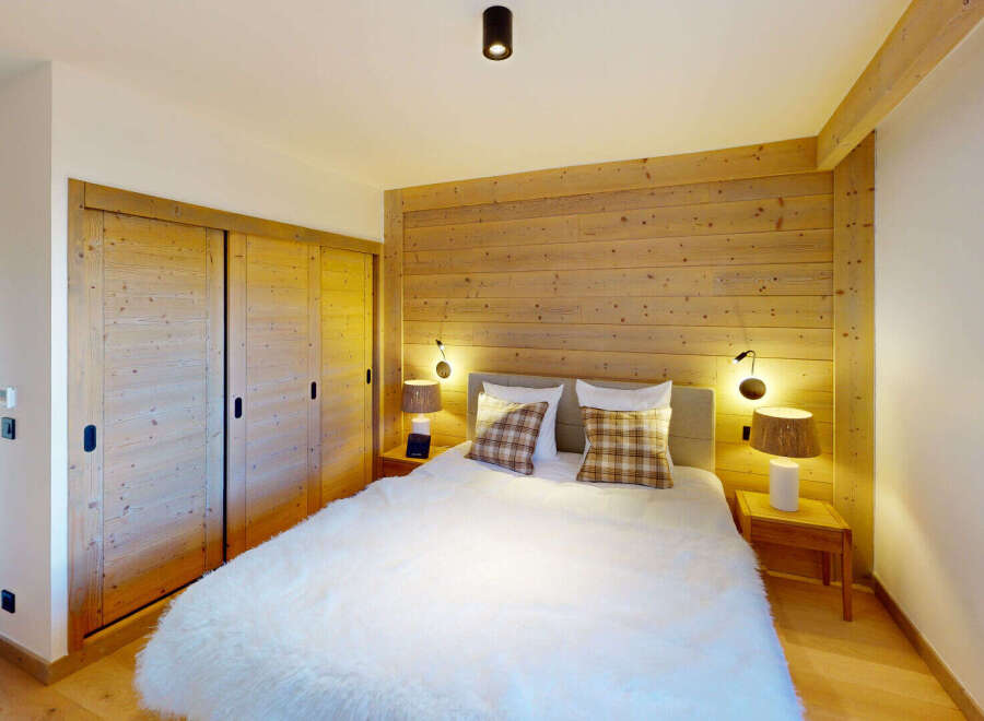 Experience cozy mountain living in this charming bedroom featuring a plush white duvet and warm wooden accents.