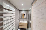 This modern bathroom features a sleek white towel warmer against a backdrop of elegant grey tiled walls.