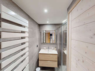 This modern bathroom features a sleek white towel warmer against a backdrop of elegant grey tiled walls.