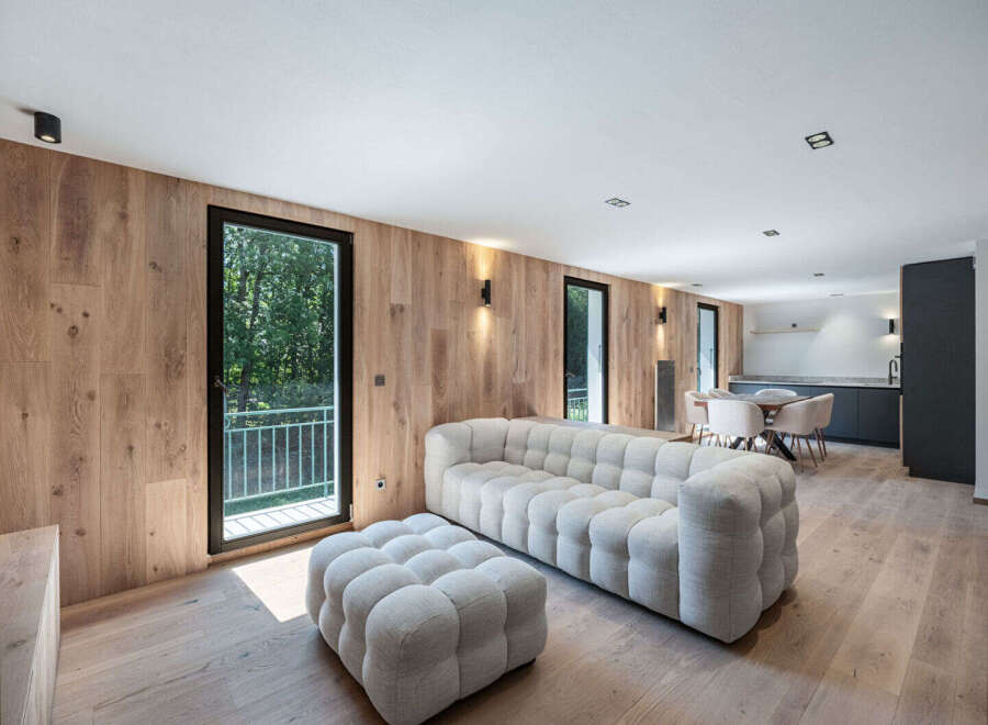 Experience modern luxury in this stunning property featuring a spacious living area with a plush, tufted sofa and ottoman.