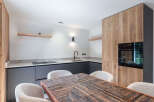 This modern kitchen features a stunning wooden dining table and cozy white chairs, perfect for family gatherings.