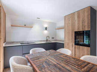 This modern kitchen features a stunning wooden dining table and cozy white chairs, perfect for family gatherings.