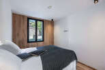 This modern bedroom features a stylish wooden accent wall and a large window offering scenic views.