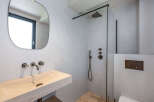 This modern bathroom features a sleek design with a stone sink and a walk-in shower.