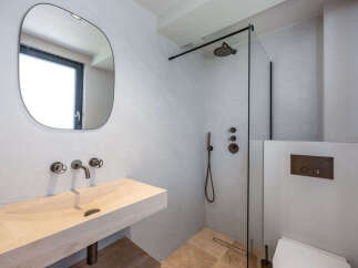 This modern bathroom features a sleek design with a stone sink and a walk-in shower.