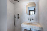 This modern bathroom showcases a minimalist design with a concrete sink and a unique, rounded mirror.