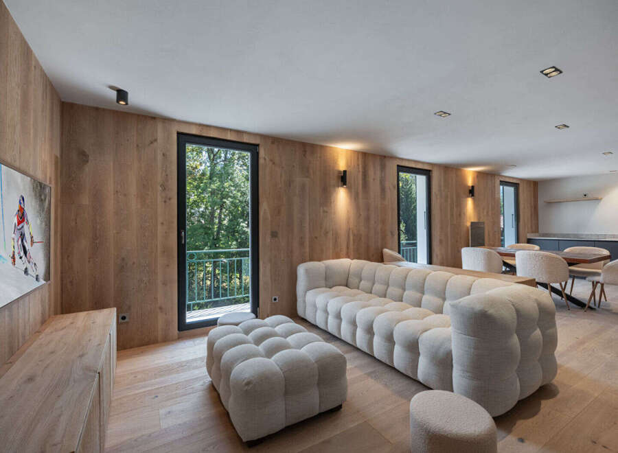 Experience luxury living in this stunning property, featuring a spacious living area with a modern, tufted sofa and ottoman.