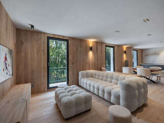 Experience luxury living in this stunning property, featuring a spacious living area with a modern, tufted sofa and ottoman.