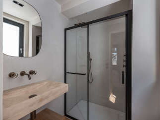 Step into a modern bathroom oasis! This stunning space features a sleek, frameless shower enclosure with black accents, complementing the contemporary design.