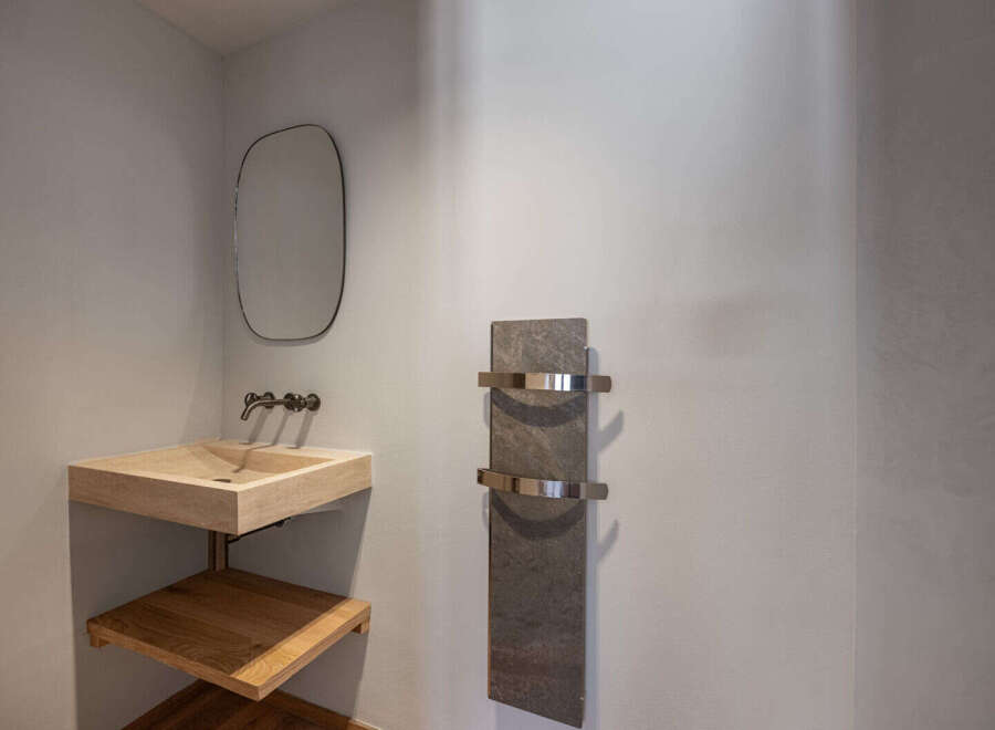 This modern bathroom features a sleek, minimalist design with a floating sink and a stylish towel warmer.