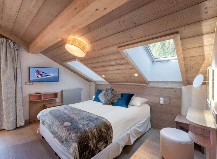 Experience the charm of this cozy bedroom, featuring a unique sloped ceiling and natural wood accents.