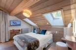 Experience the charm of this cozy bedroom, featuring a unique sloped ceiling and natural wood accents.