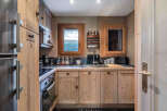 This charming kitchen boasts rustic wooden cabinetry and a stainless steel sink, creating a warm and inviting atmosphere.
