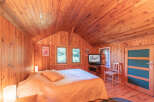 Step into this charming cabin bedroom, featuring warm wood paneling and a cozy atmosphere.