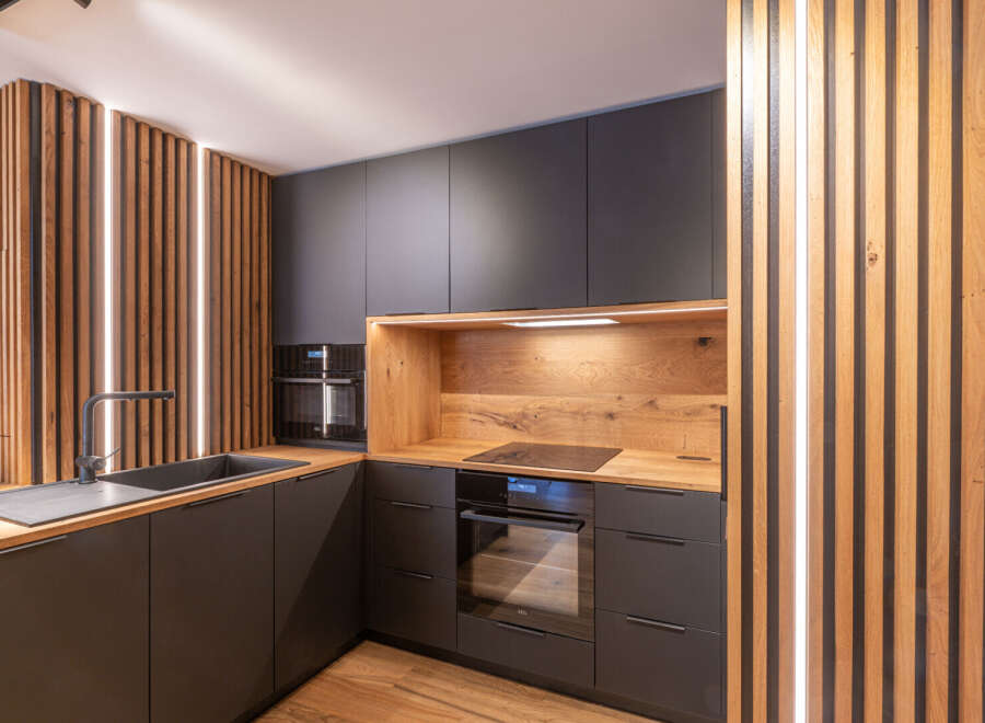 This modern kitchen boasts sleek, dark cabinetry complemented by warm wood accents, creating a stylish and inviting atmosphere.