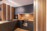 This modern kitchen boasts sleek, dark cabinetry complemented by warm wood accents, creating a stylish and inviting atmosphere.