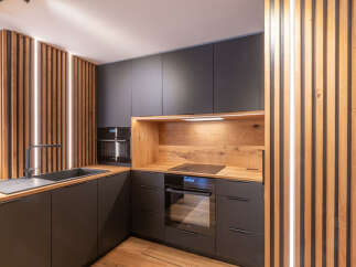 This modern kitchen boasts sleek, dark cabinetry complemented by warm wood accents, creating a stylish and inviting atmosphere.
