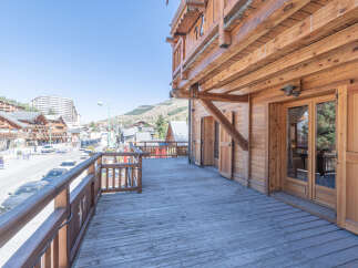Experience the charm of this stunning wooden chalet with a spacious deck overlooking a picturesque mountain town.
