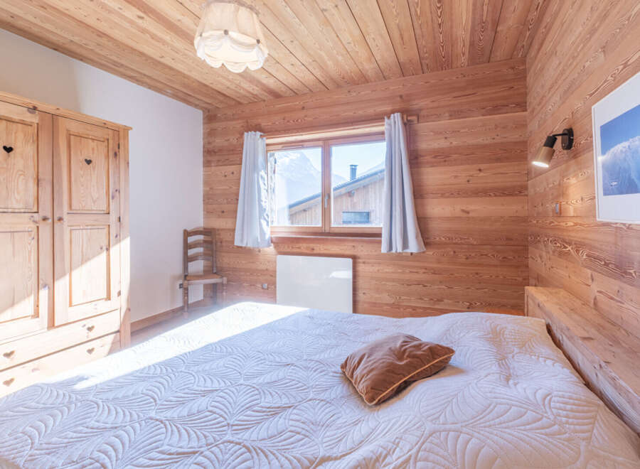 This cozy bedroom features beautiful wooden paneling on the walls and ceiling, creating a warm and inviting atmosphere.