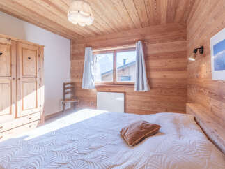 This cozy bedroom features beautiful wooden paneling on the walls and ceiling, creating a warm and inviting atmosphere.