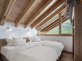 This cozy bedroom features a unique sloped ceiling with exposed wooden beams, creating a warm and inviting atmosphere.