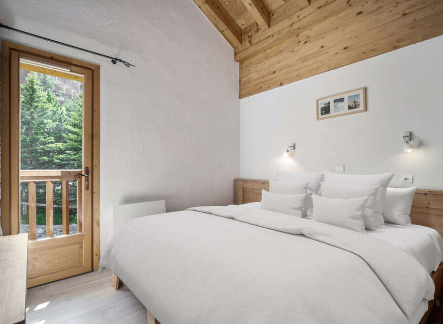 Experience the tranquility of this charming bedroom, featuring a cozy bed and a stunning view of the surrounding nature.