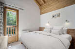 Experience the tranquility of this charming bedroom, featuring a cozy bed and a stunning view of the surrounding nature.