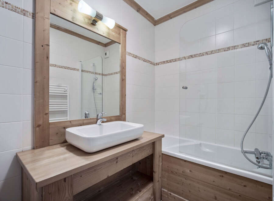 This charming bathroom features a rustic wooden vanity and mirror frame, creating a warm and inviting atmosphere.