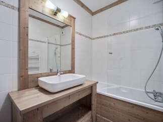 This charming bathroom features a rustic wooden vanity and mirror frame, creating a warm and inviting atmosphere.