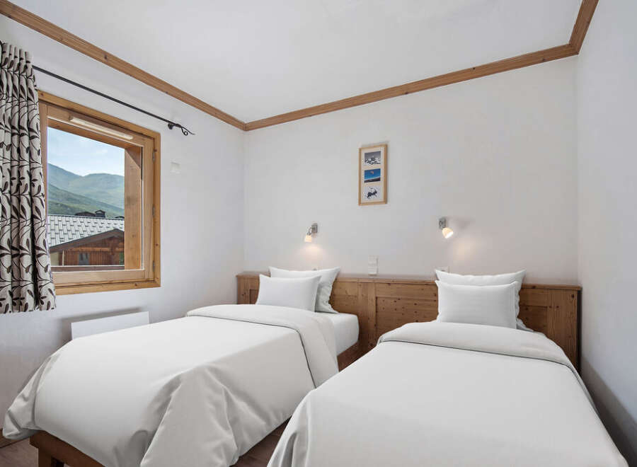 This cozy bedroom features two twin beds with crisp white linens, perfect for a comfortable stay.