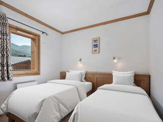 This cozy bedroom features two twin beds with crisp white linens, perfect for a comfortable stay.