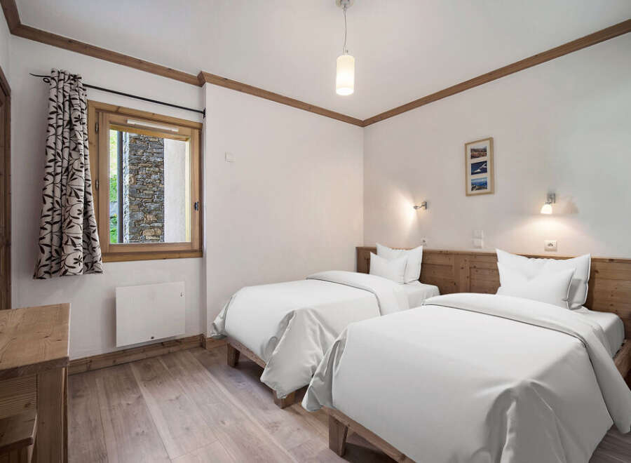 This cozy bedroom features two twin beds with crisp white linens, perfect for a comfortable stay.