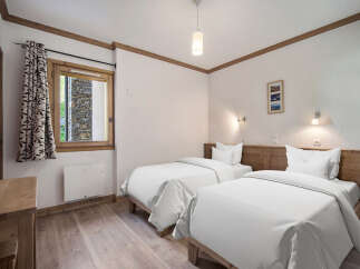 This cozy bedroom features two twin beds with crisp white linens, perfect for a comfortable stay.
