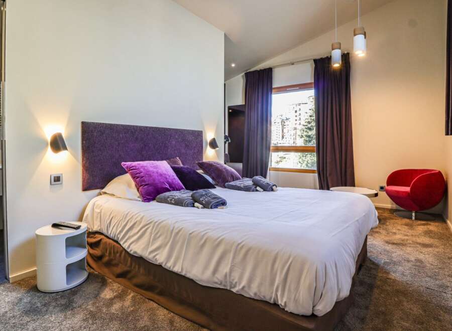 Experience luxury in this stunning bedroom! Featuring a plush bed with vibrant purple accents, this space is designed for ultimate comfort.